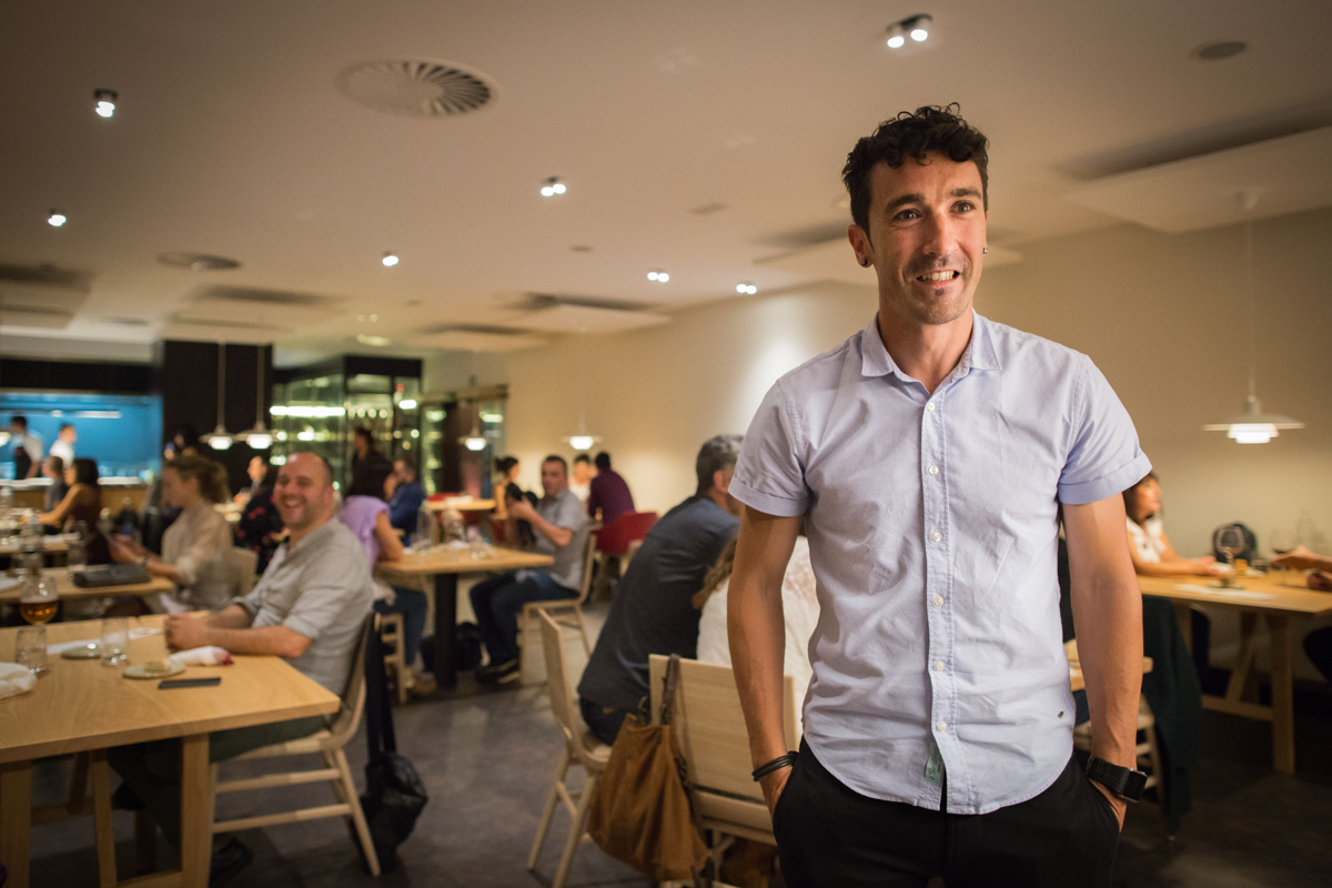 Eneko posa en el restaurante con los comensales de fondo.